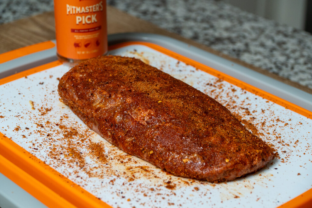 raw pork loin with seasoning all over it on a white board