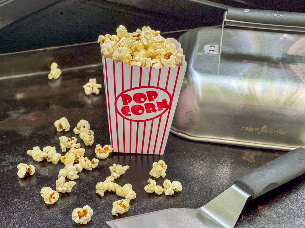 popcorn in a paper cup with some spilt out of it