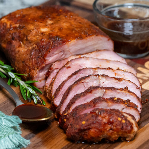 a sliced piece of cooked pork loin on a wooden board