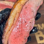 gloved hand holding smoked picanha steak