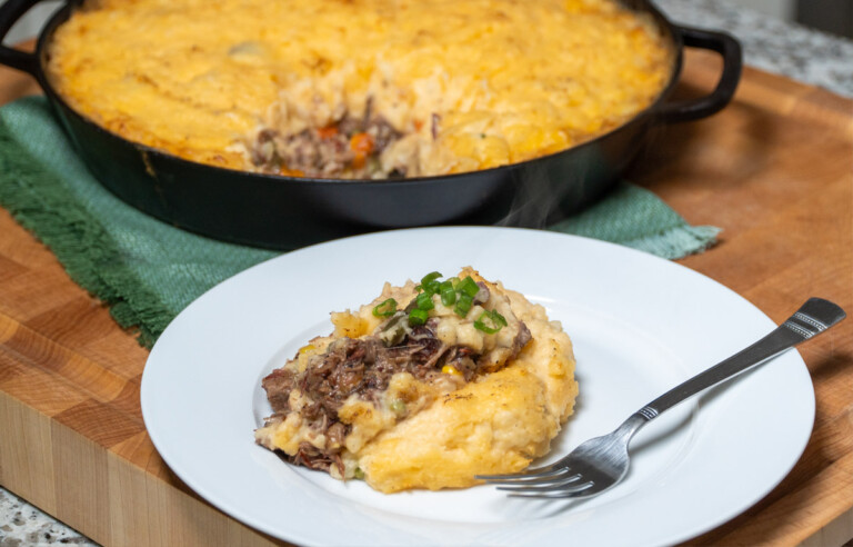 a spoonful of brisket shepherds pie on a white plate with a fork