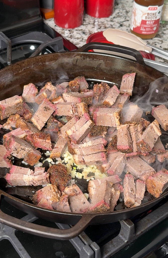 cubes of brisket in a pan with shallots