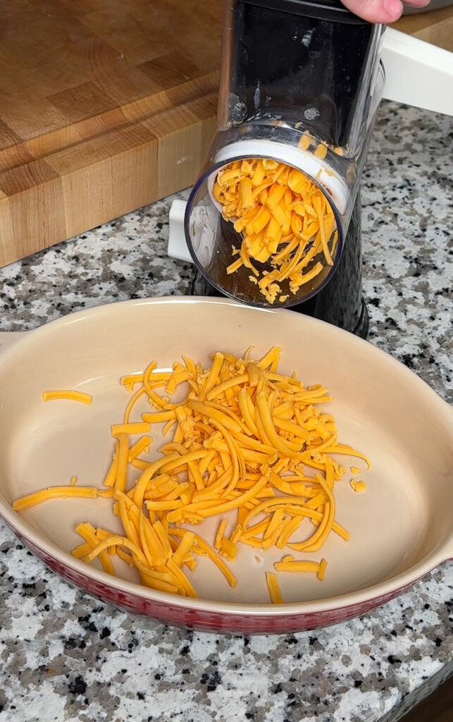 a grater shredding cheese in a beige bowl