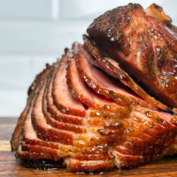 Glazed, spiral-cut smoked ham with a caramelized crust, sliced and ready to serve. Click for the best smoked ham recipes.