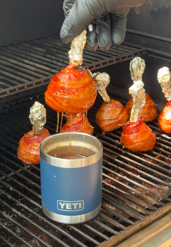 a single chicken lollipop being dunked in bbq sauce