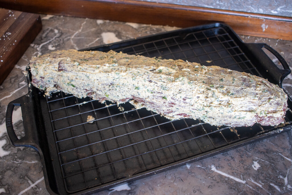 a beef tenderloin slathered in garlic butter compound sittingon a wire rack