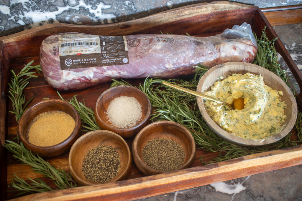 the ingredients for smoked beef tenderloin laid out on a wooden tray