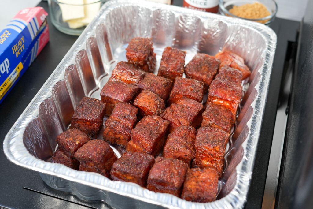 cooked bacon burnt ends in a foil tray