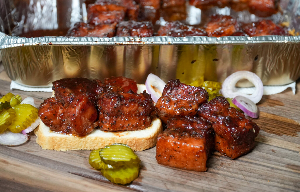 smoked burnt bacon ends presented on bread with pickles