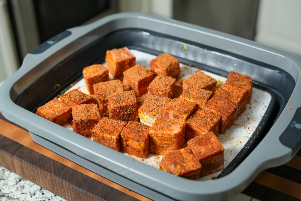 raw seasoned cubes of bacon in a tray