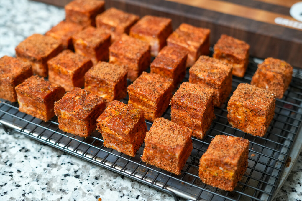 raw seasoned bacon cubes on a wire rack on a marble benchtop