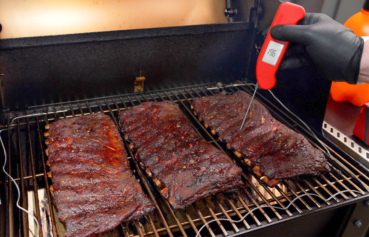 3 racks of ribs, one with an instant read thermometer in it