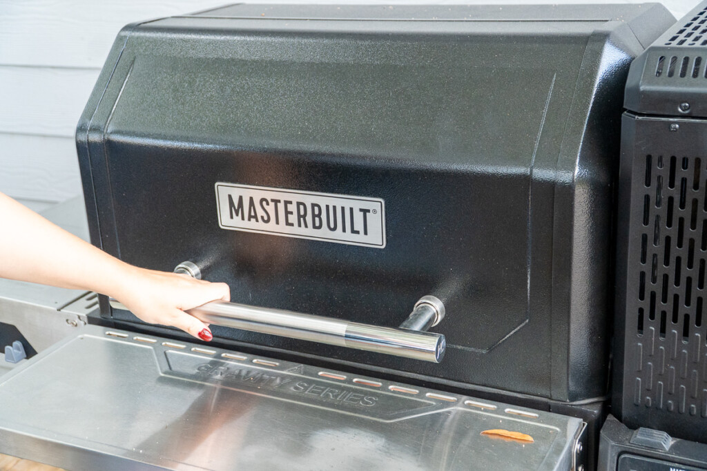 a woman opening the Masterbuilt Gravity XT grill door