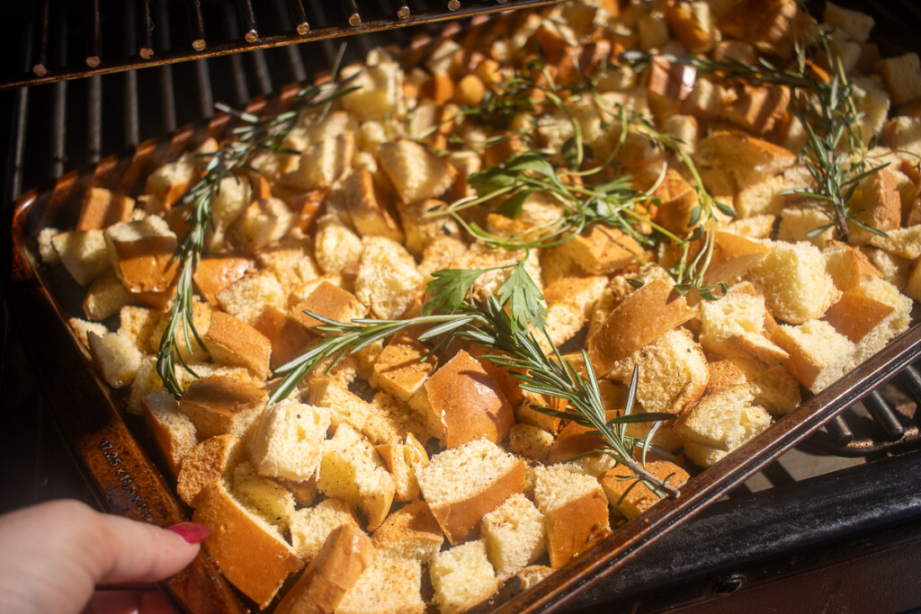 brioche cubes in a metal tray with herbs