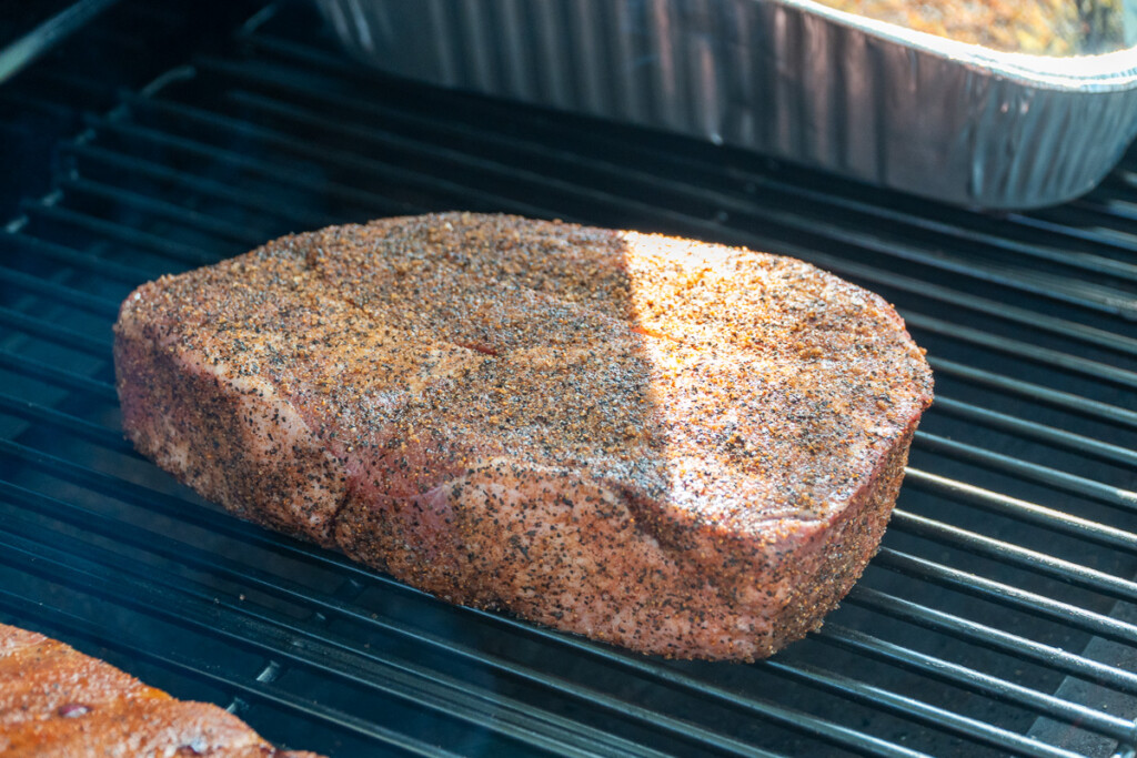 a raw, seasoned piece of meat in the smoker