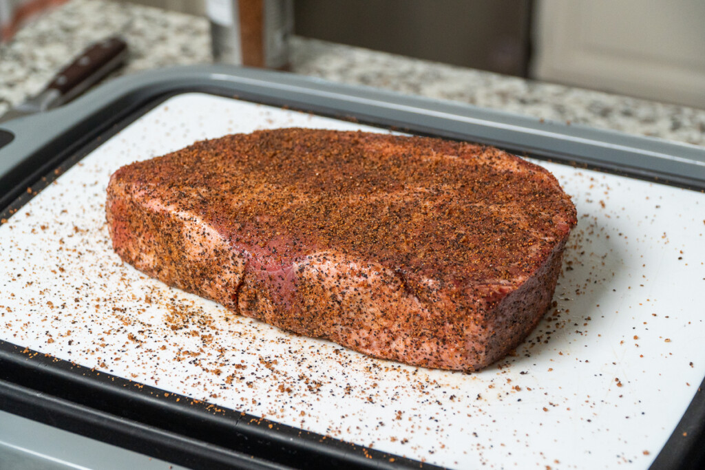 a seasoned, raw piece of meat on a white board