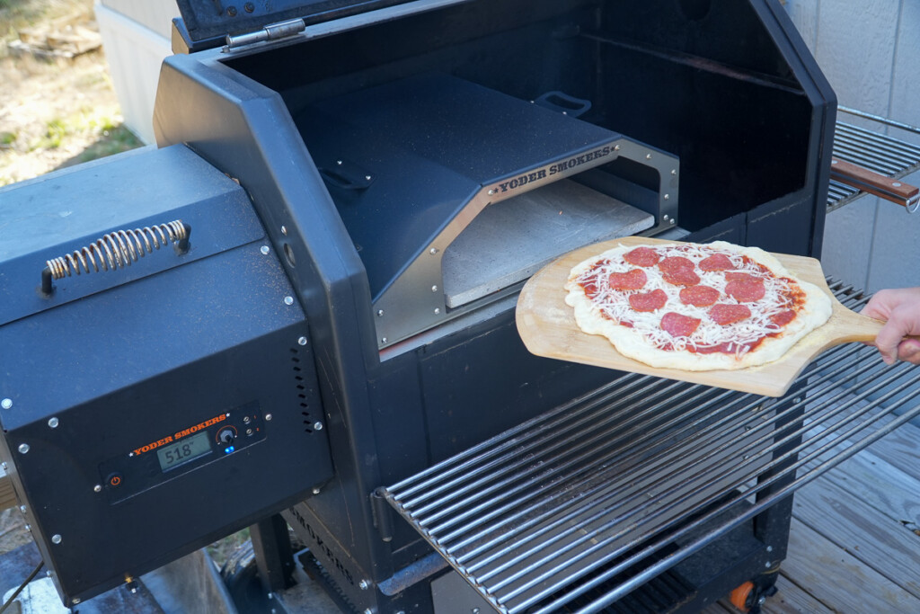 uncooked pizza being fed into the pizza oven
