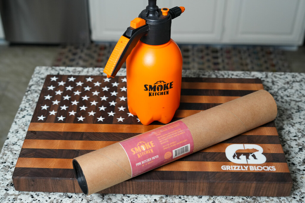 a bbq sprayer and pink butcher paper on a wooden board