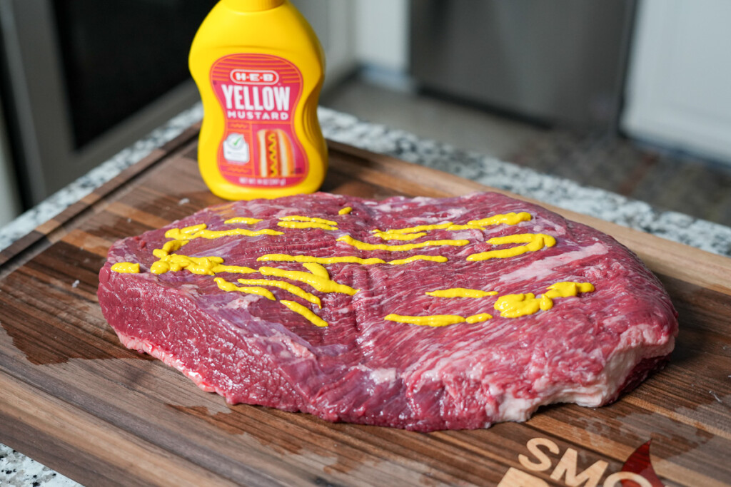 a raw piece of brisket flat with yellow mustard on it