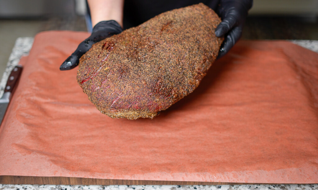 step one of wrapping a brisket with pink butcher paper
