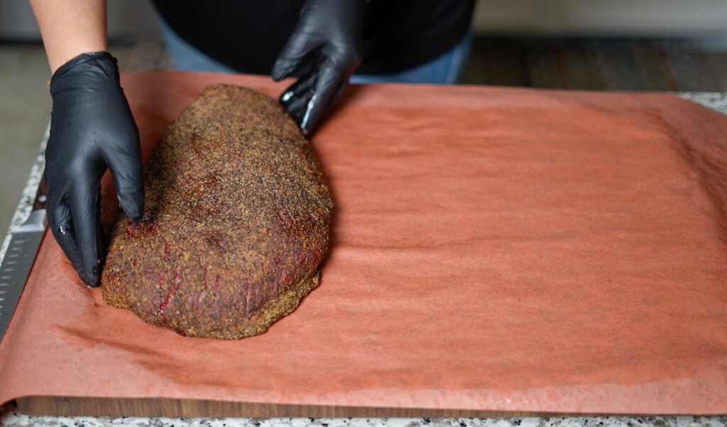 step two of wrapping a brisket in pink butcher paper