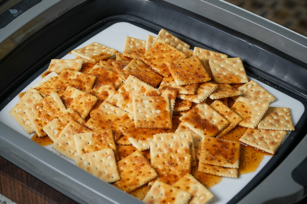 crackers in a grey bowl with oil and seasoning poured over them