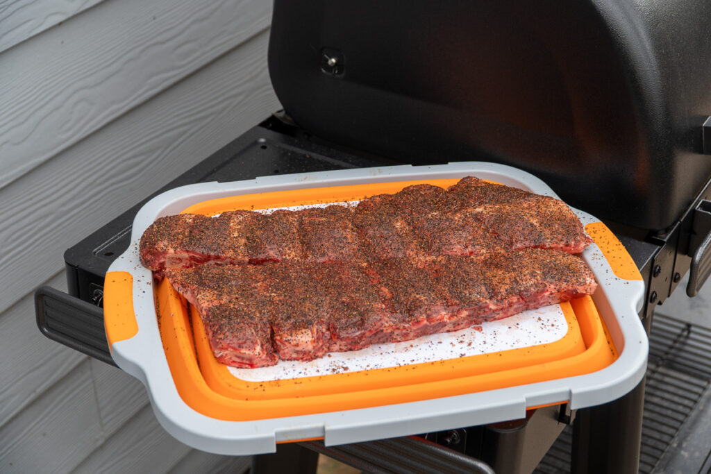 Seasoned beef back ribs on a cutting board, ready to be placed on the smoker.