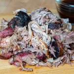 Smoked pulled pork piled on a wooden board – click for pulled pork smoker recipes