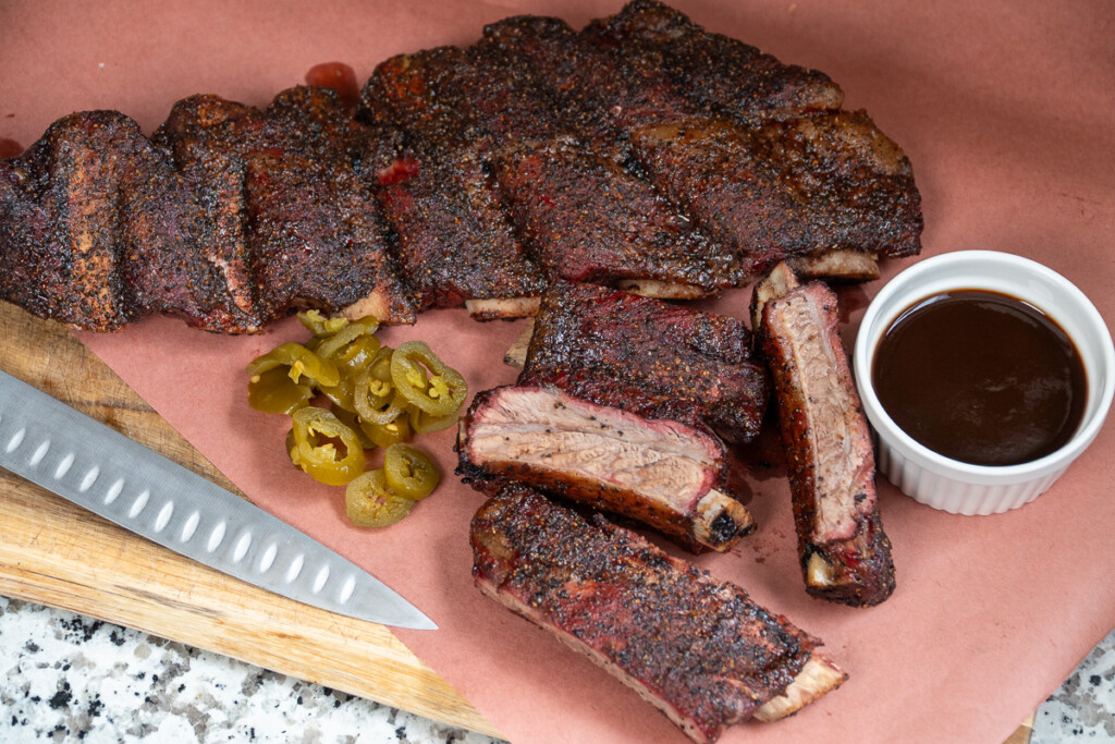 smoked beef back ribs laid out on pink butcher paper with sauce and condiments