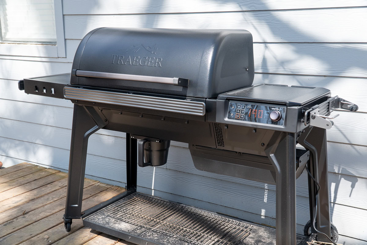 Full view of the Traeger Woodridge Pro pellet grill showing the cart-style design, front shelf, and side table.