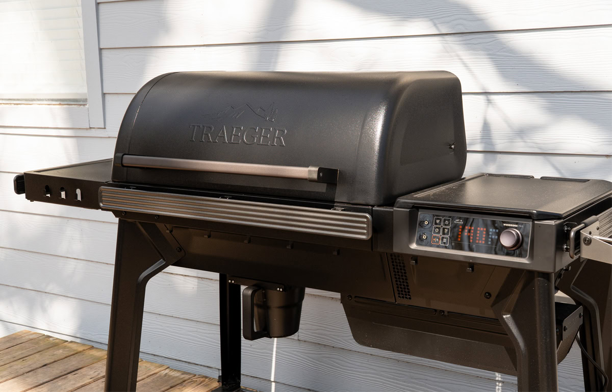 Side view of the Traeger Woodridge Pro pellet grill showing the closed lid, digital controller display, and side table.