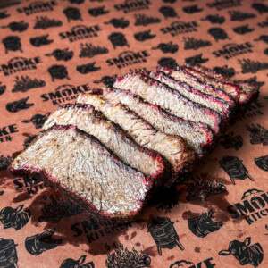 Smoked chuck roast sliced like brisket with visible smoke ring and bark on butcher paper