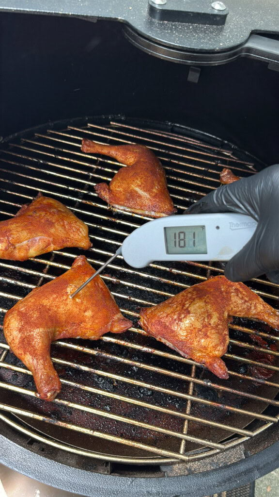 taking the internal temperature of a chicken quarter on the grill