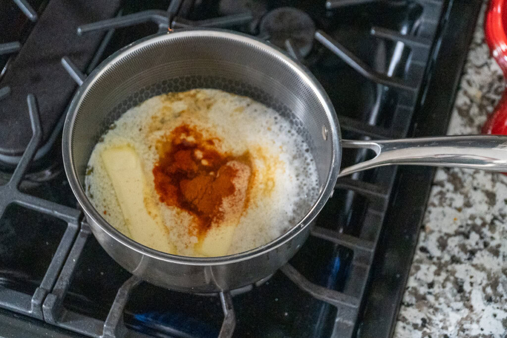 a pot with bouillion and butter and seasoning in it