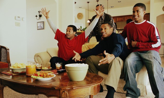 Three generations of men cheering in living room