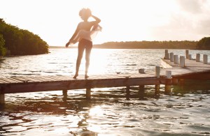 Young woman looking out to sea from boat dock.