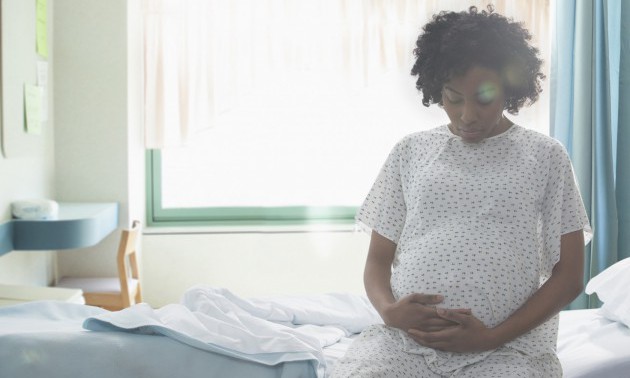 Pregnant African American woman holding her stomach in hospital