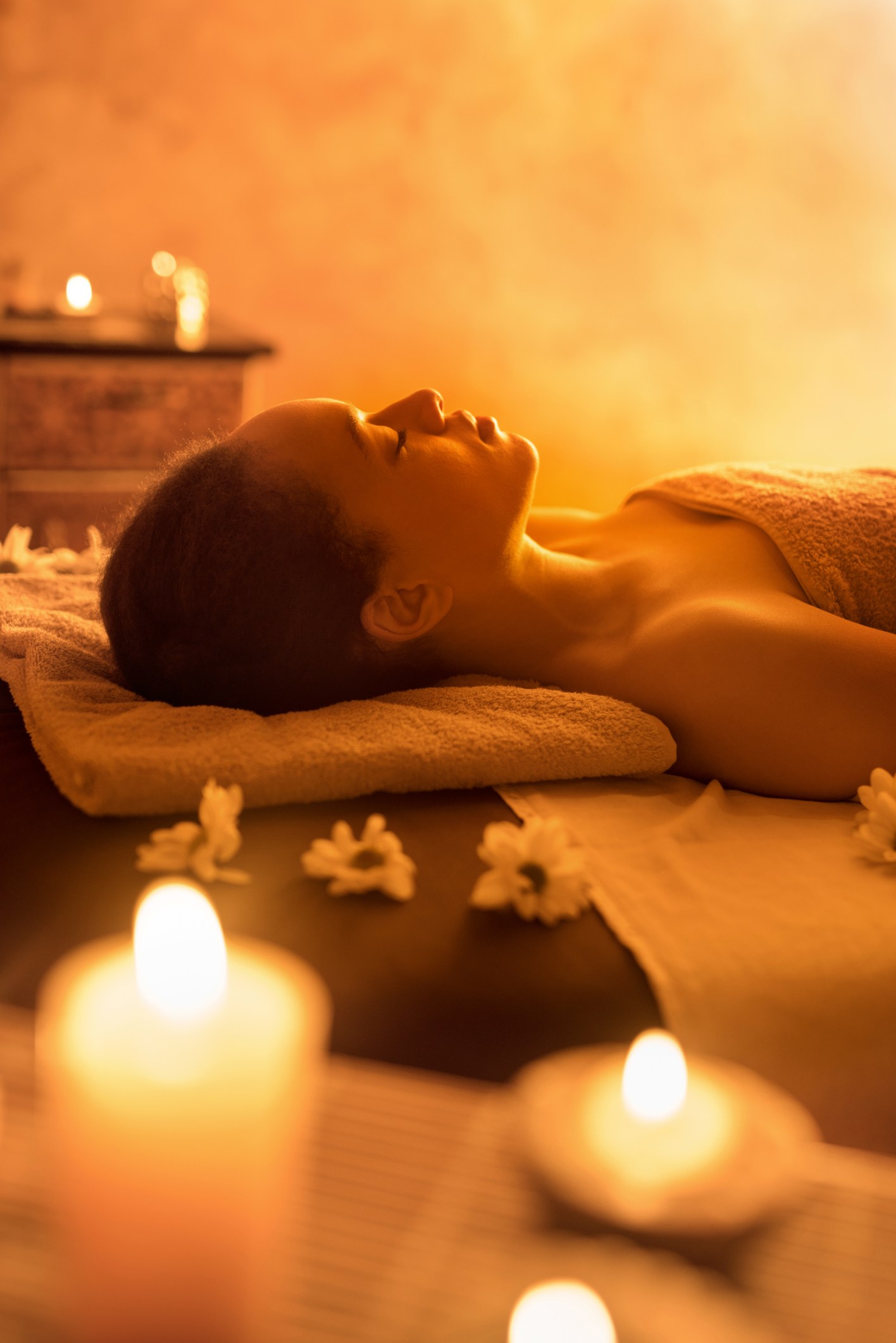 African American woman lying at spa with eyes closed.