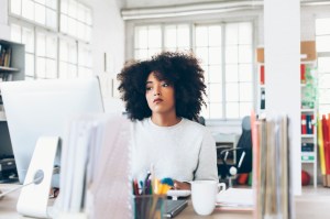 Depressed young woman using computer at the office