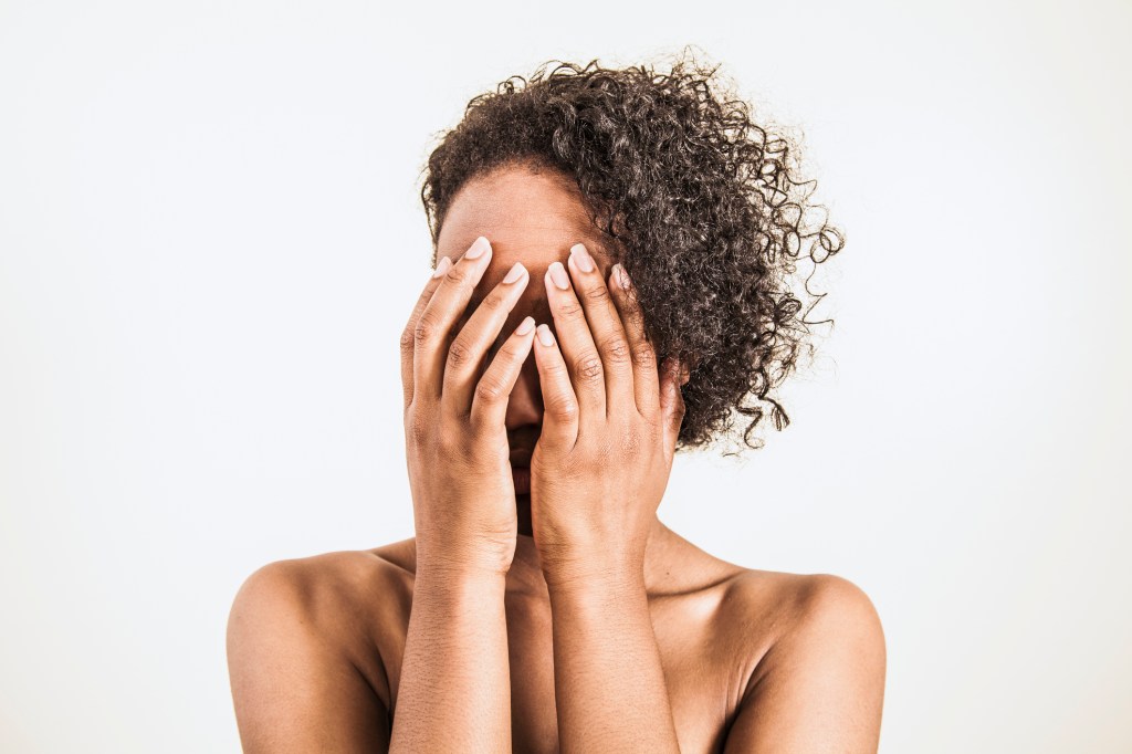 A young woman covering her face with her hands