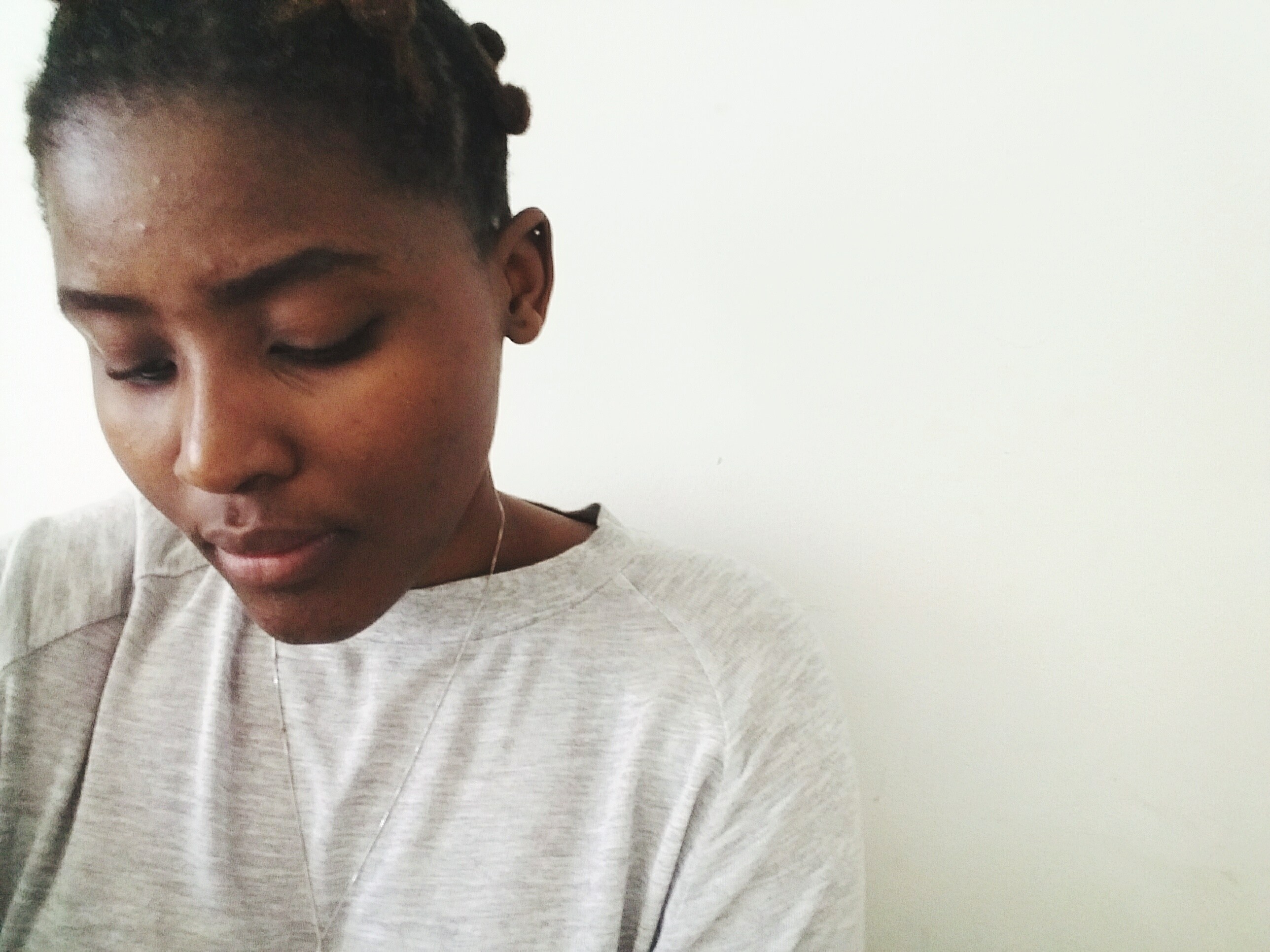 Thoughtful Woman Looking Down Against White Wall