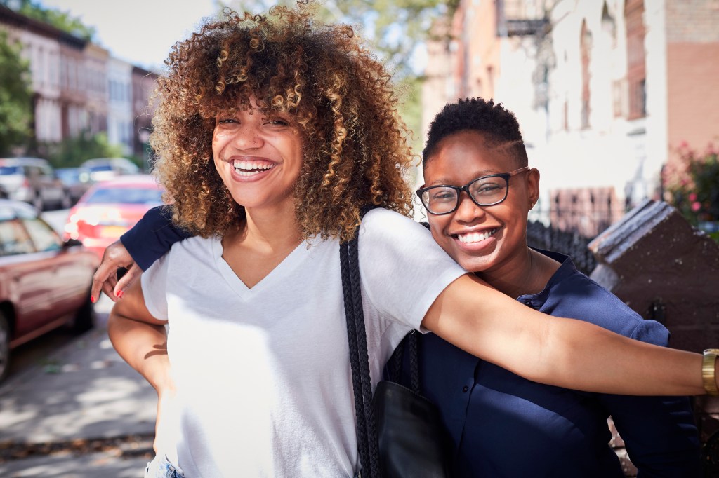 Portrait of Black women hugging on city sidewalk