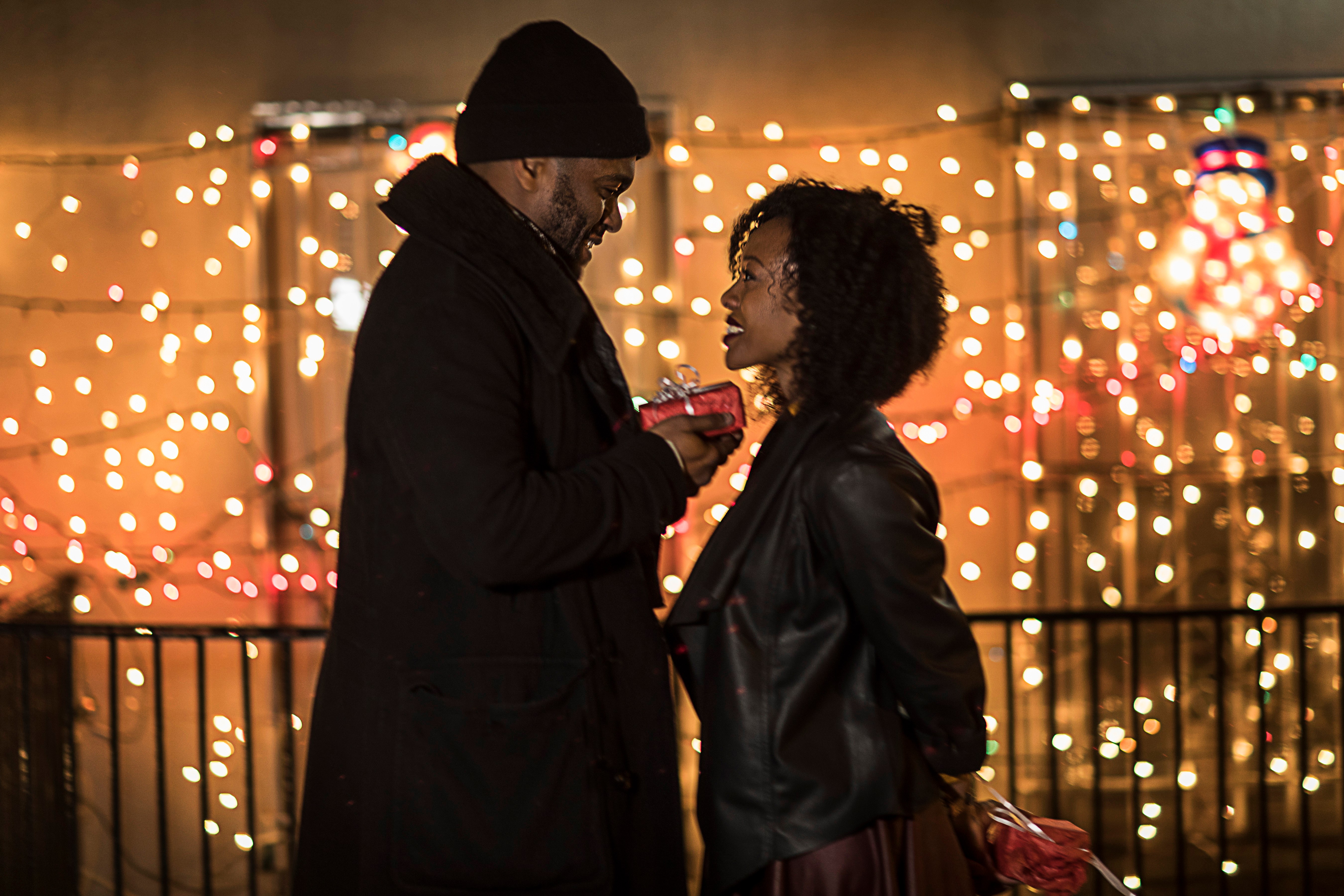 Romantic couple handing christmas gifts at night, New York, USA