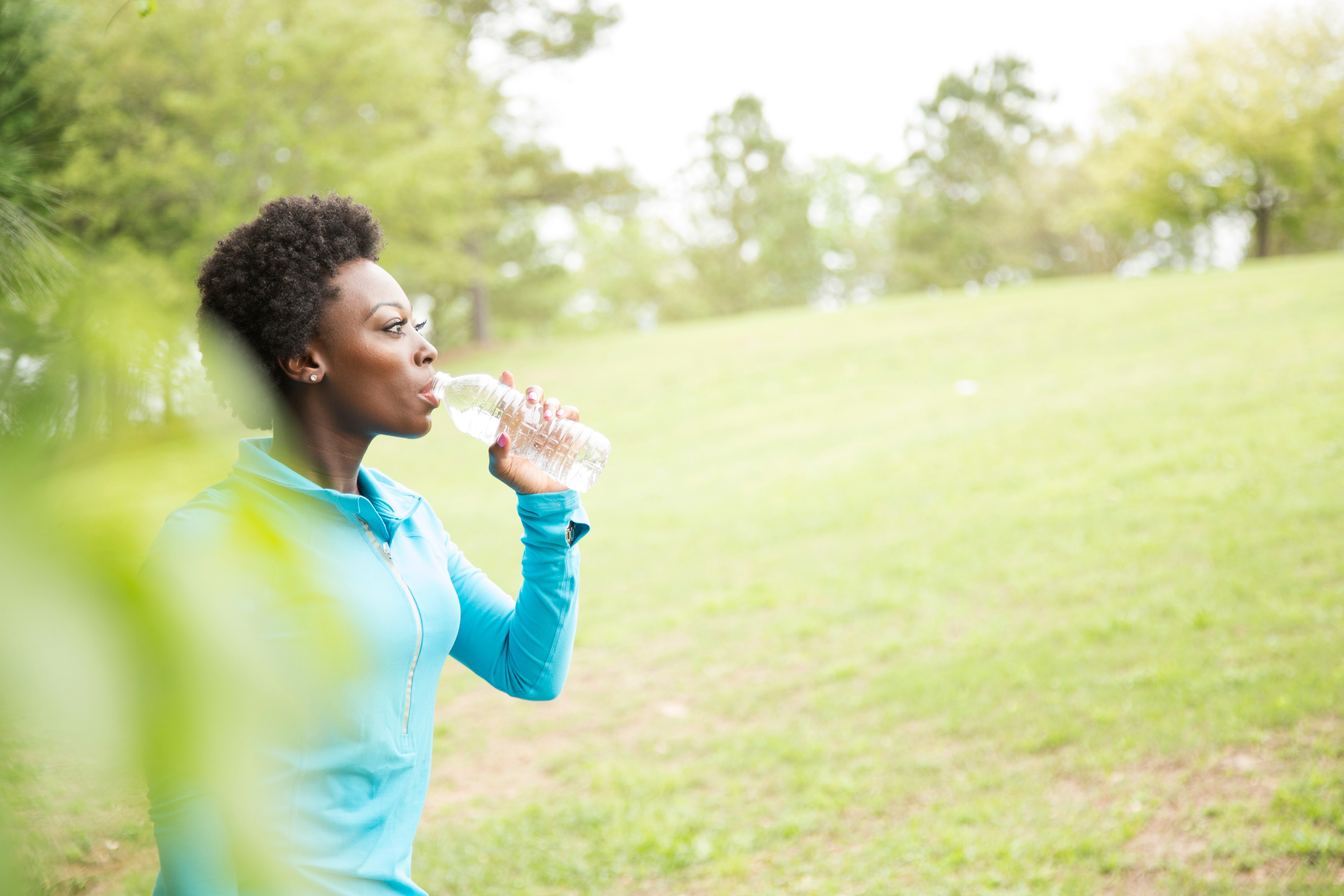 One African descent woman takes water break in neighborhood park.