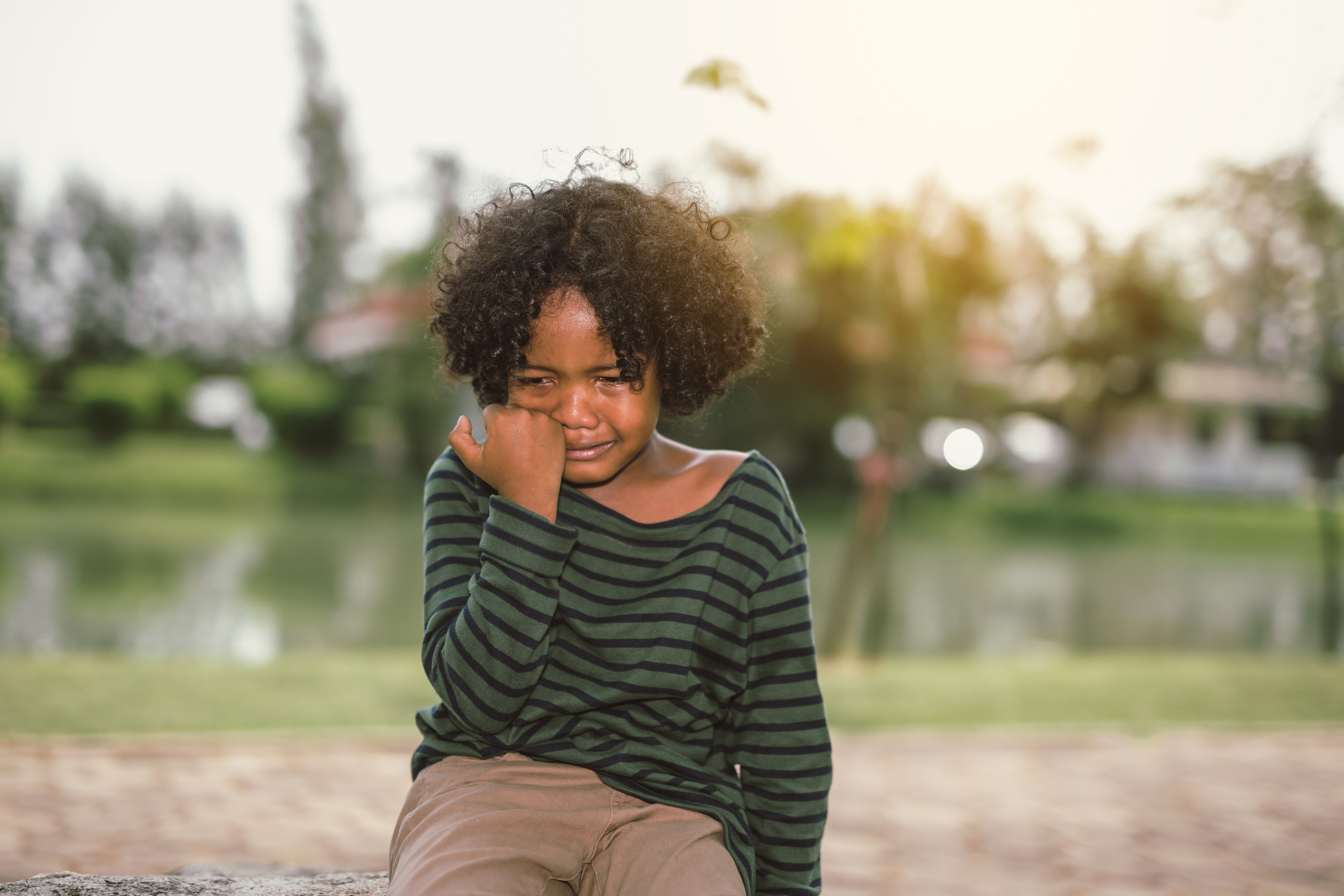 Sad Boy Crying While Sitting At Park