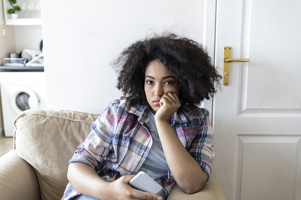 Sad african woman social networking at home