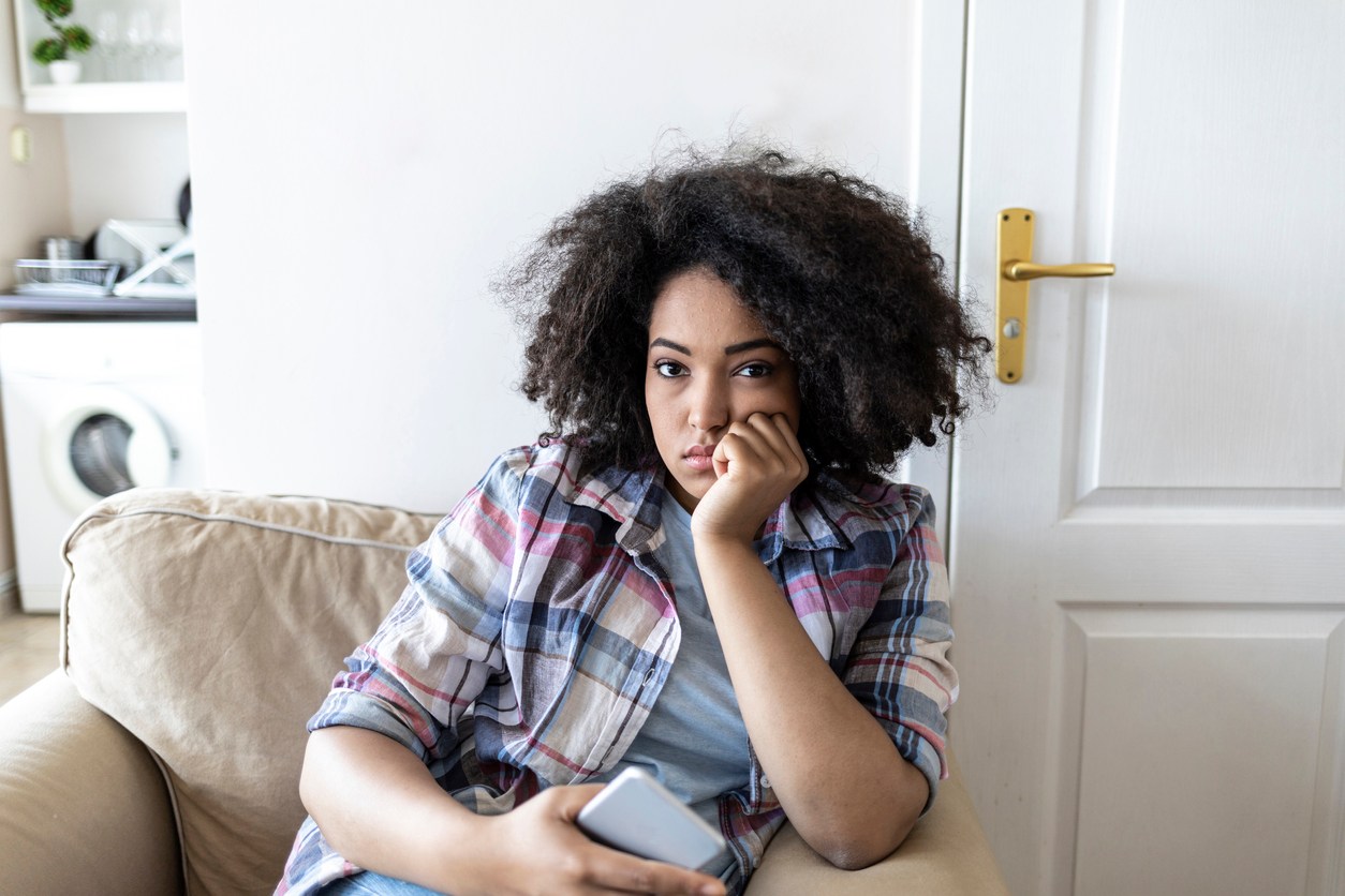 Sad african woman social networking at home