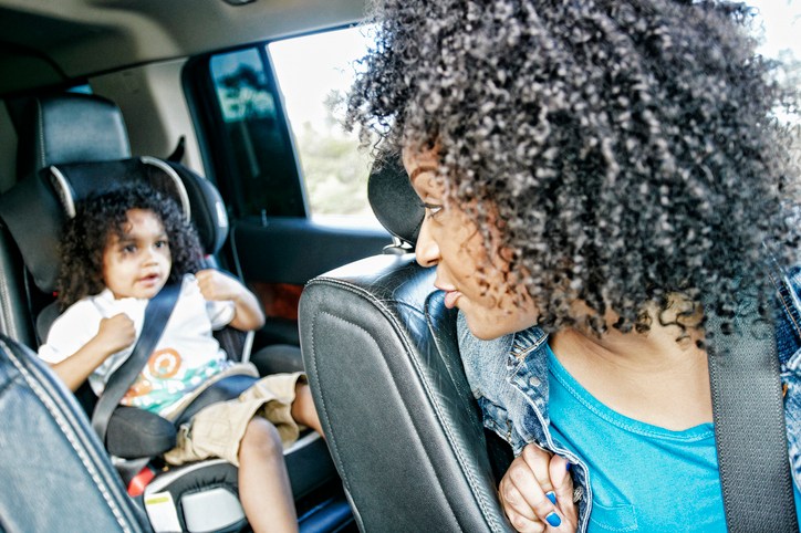 Mixed race and mother checking daughter in car seat
