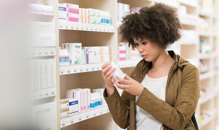 Young Woman Choosing Supplement In Drugstore