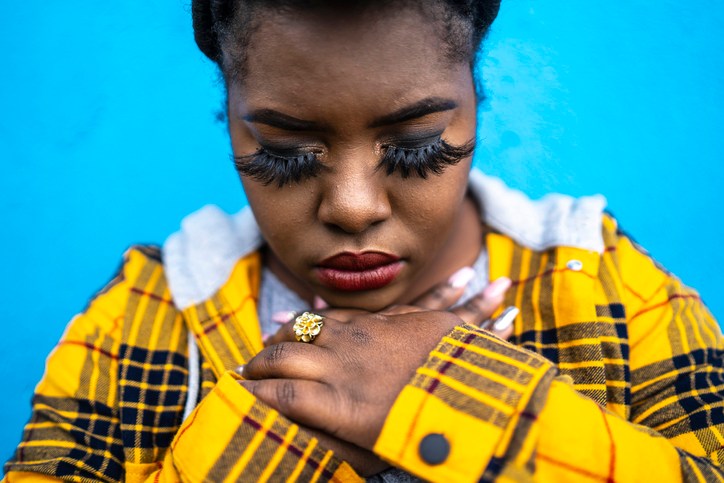 Young african woman standing arms crossed in front of color background